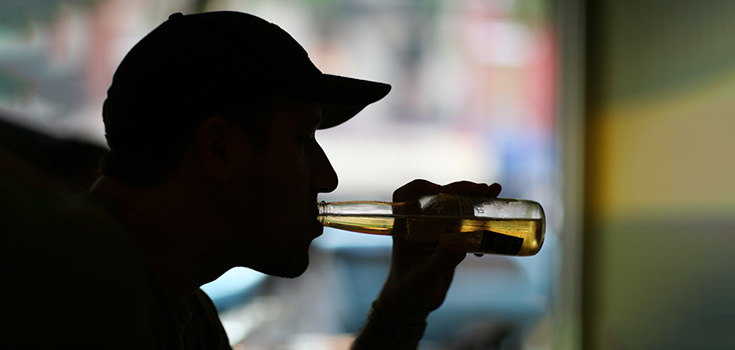 man drinking a glass bottle of beer
