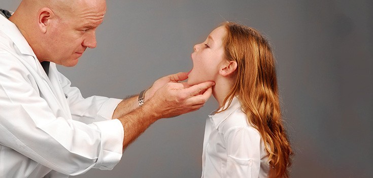 doctor checking girl's sore throat