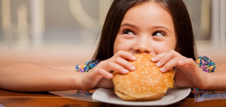 little girl eating hamburger