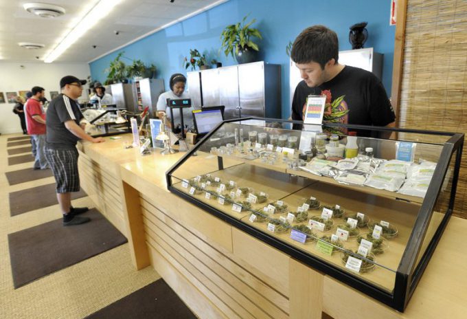 Employee Derek Flores, right, waits for a patient at a display case at the Harborside Health Center in Oakland, Calif. The center will be one of the models for Maine's first medical marijuana dispensaries. Credit: John Patriquin/Staff Photographer